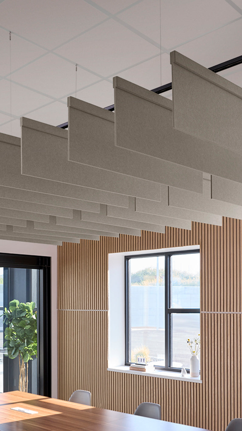 Light brownish-grey acoustic ceiling blade baffles suspended from the ceiling, installed in a conference room. Felt Right's acoustic blade baffles absorb 65% of sound waves, making office spaces quieter and feel more calm.