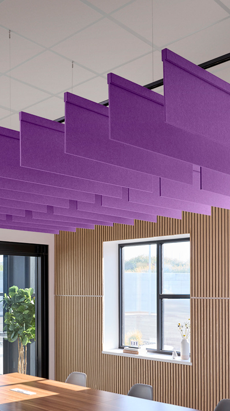 Purple acoustic ceiling blade baffles suspended from the ceiling, installed in a conference room. Felt Right's acoustic blade baffles absorb 65% of sound waves, making office spaces quieter and feel more calm.