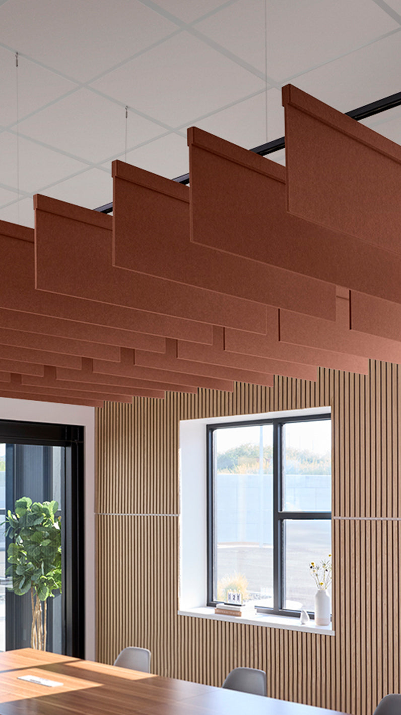 Reddish-brown acoustic ceiling blade baffles suspended from the ceiling, installed in a conference room. Felt Right's acoustic blade baffles absorb 65% of sound waves, making office spaces quieter and feel more calm.