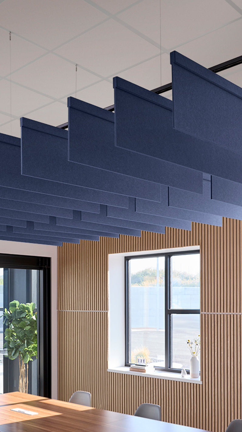 Dark blue acoustic ceiling blade baffles suspended from the ceiling, installed in a conference room. Felt Right's acoustic blade baffles absorb 65% of sound waves, making office spaces quieter and feel more calm.