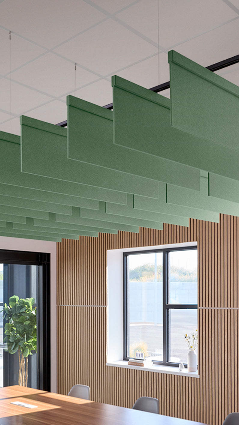 Green acoustic ceiling blade baffles suspended from the ceiling, installed in a conference room. Felt Right's acoustic blade baffles absorb 65% of sound waves, making office spaces quieter and feel more calm.