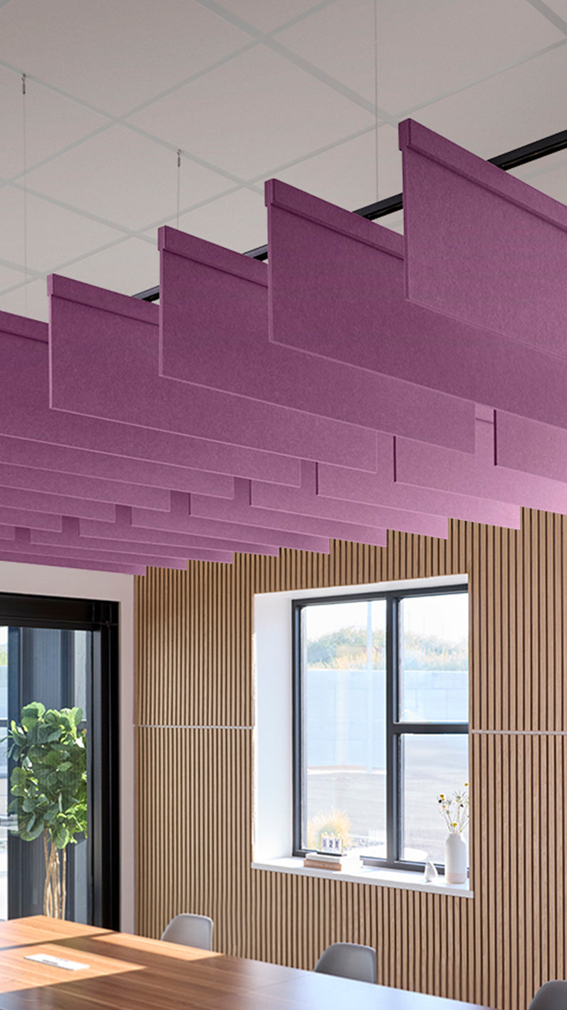 Reddish-purple acoustic ceiling blade baffles suspended from the ceiling, installed in a conference room. Felt Right's acoustic blade baffles absorb 65% of sound waves, making office spaces quieter and feel more calm.