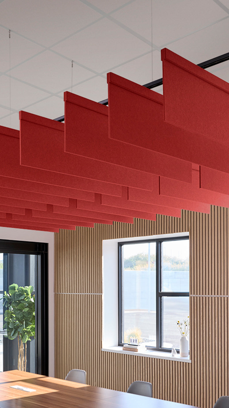 Bright red acoustic ceiling blade baffles suspended from the ceiling, installed in a conference room. Felt Right's acoustic blade baffles absorb 65% of sound waves, making office spaces quieter and feel more calm.
