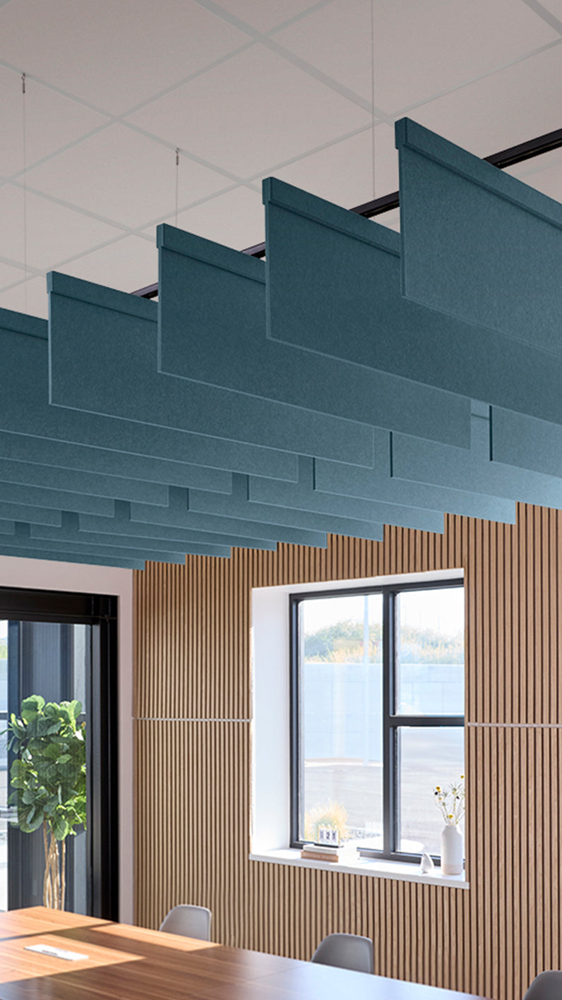 Teal acoustic ceiling blade baffles suspended from the ceiling, installed in a conference room. Felt Right's acoustic blade baffles absorb 65% of sound waves, making office spaces quieter and feel more calm.