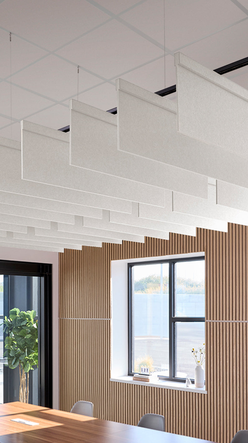 White acoustic ceiling blade baffles suspended from the ceiling, installed in a conference room. Felt Right's acoustic blade baffles absorb 65% of sound waves, making office spaces quieter and feel more calm.
