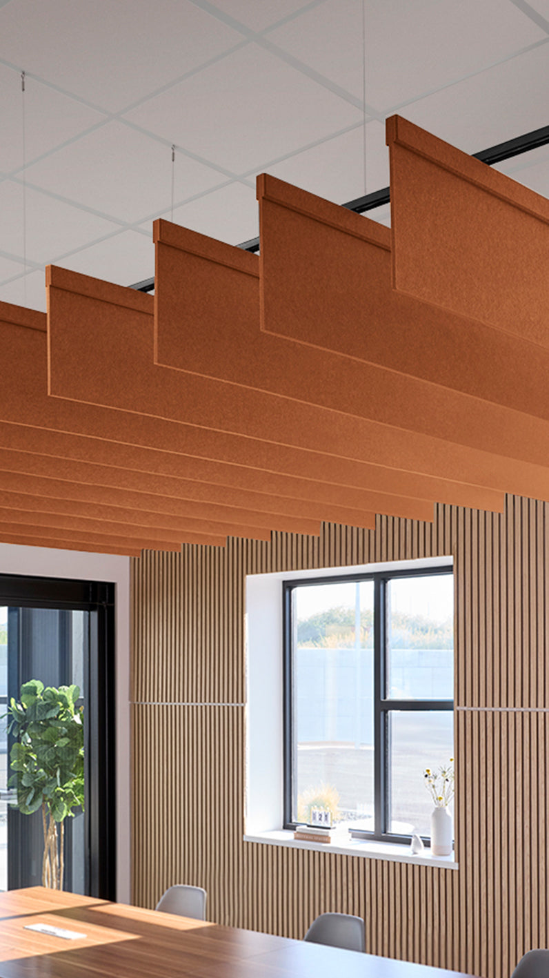 Dark orange acoustic ceiling blade baffles suspended from the ceiling, installed in a conference room. Felt Right's acoustic blade baffles absorb 65% of sound waves, making office spaces quieter and feel more calm.