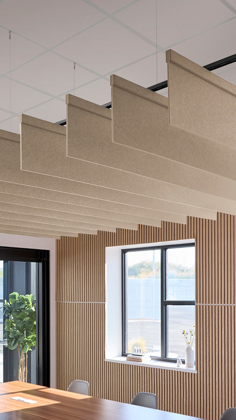 Creamy beige acoustic ceiling blade baffles suspended from the ceiling, installed in a conference room. Felt Right's acoustic blade baffles absorb 65% of sound waves, making office spaces quieter and feel more calm.