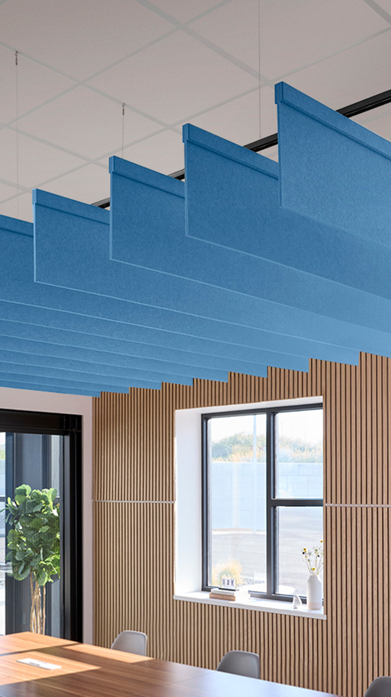 Bright blue acoustic ceiling blade baffles suspended from the ceiling, installed in a conference room. Felt Right's acoustic blade baffles absorb 65% of sound waves, making office spaces quieter and feel more calm.