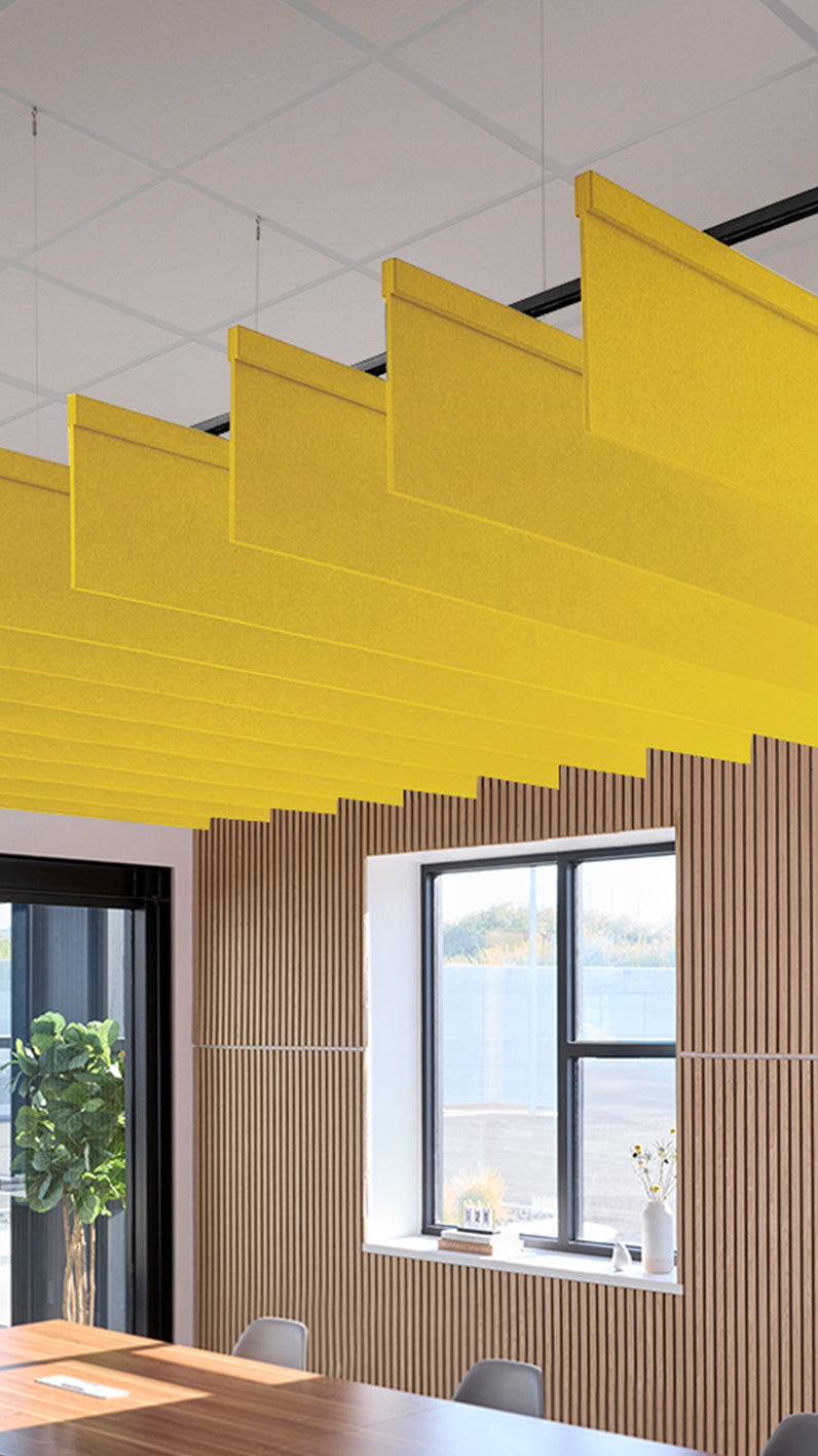 Yellow acoustic ceiling blade baffles suspended from the ceiling, installed in a conference room. Felt Right's acoustic blade baffles absorb 65% of sound waves, making office spaces quieter and feel more calm.