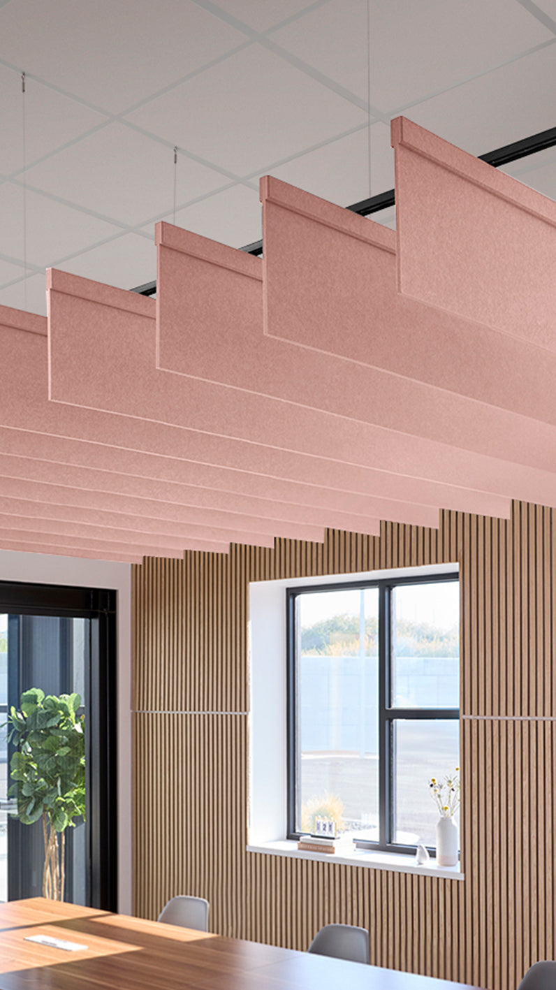 Soft pink acoustic ceiling blade baffles suspended from the ceiling, installed in a conference room. Felt Right's acoustic blade baffles absorb 65% of sound waves, making office spaces quieter and feel more calm.