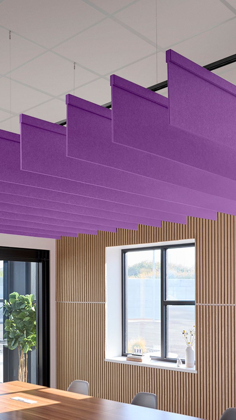 Purple acoustic ceiling blade baffles suspended from the ceiling, installed in a conference room. Felt Right's acoustic blade baffles absorb 65% of sound waves, making office spaces quieter and feel more calm.