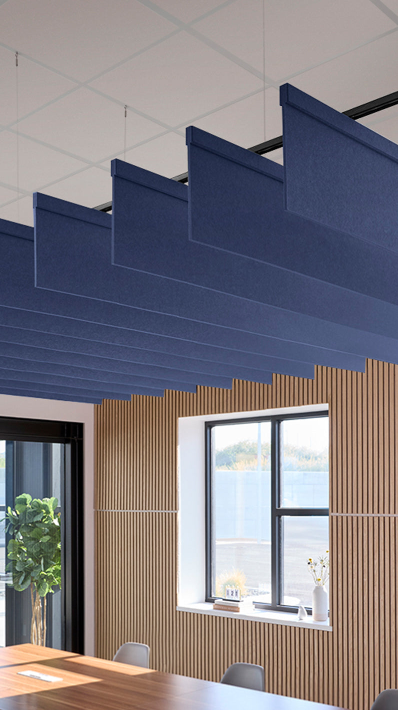 Dark blue acoustic ceiling blade baffles suspended from the ceiling, installed in a conference room. Felt Right's acoustic blade baffles absorb 65% of sound waves, making office spaces quieter and feel more calm.