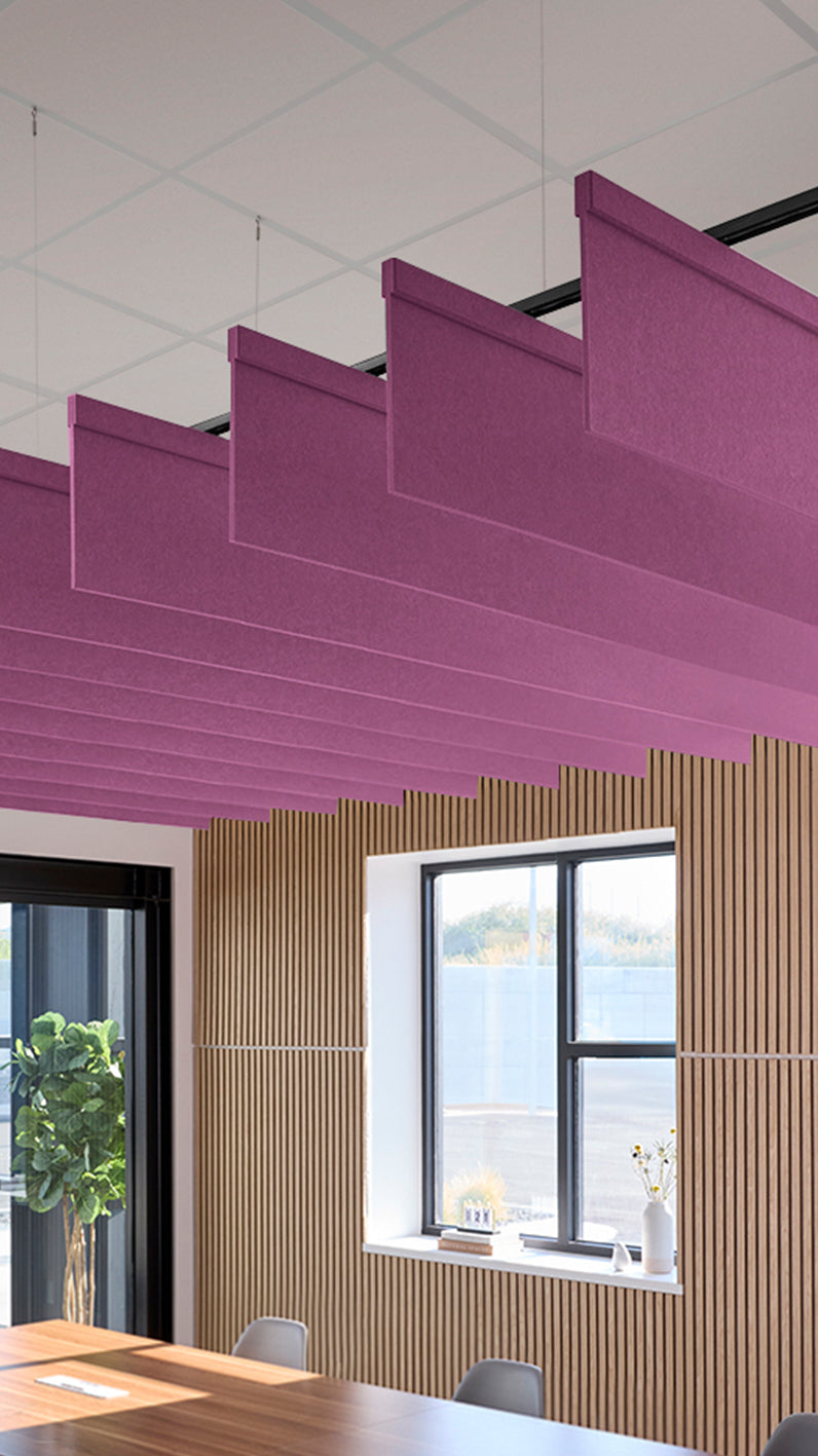 Reddish-purple acoustic ceiling blade baffles suspended from the ceiling, installed in a conference room. Felt Right's acoustic blade baffles absorb 65% of sound waves, making office spaces quieter and feel more calm.