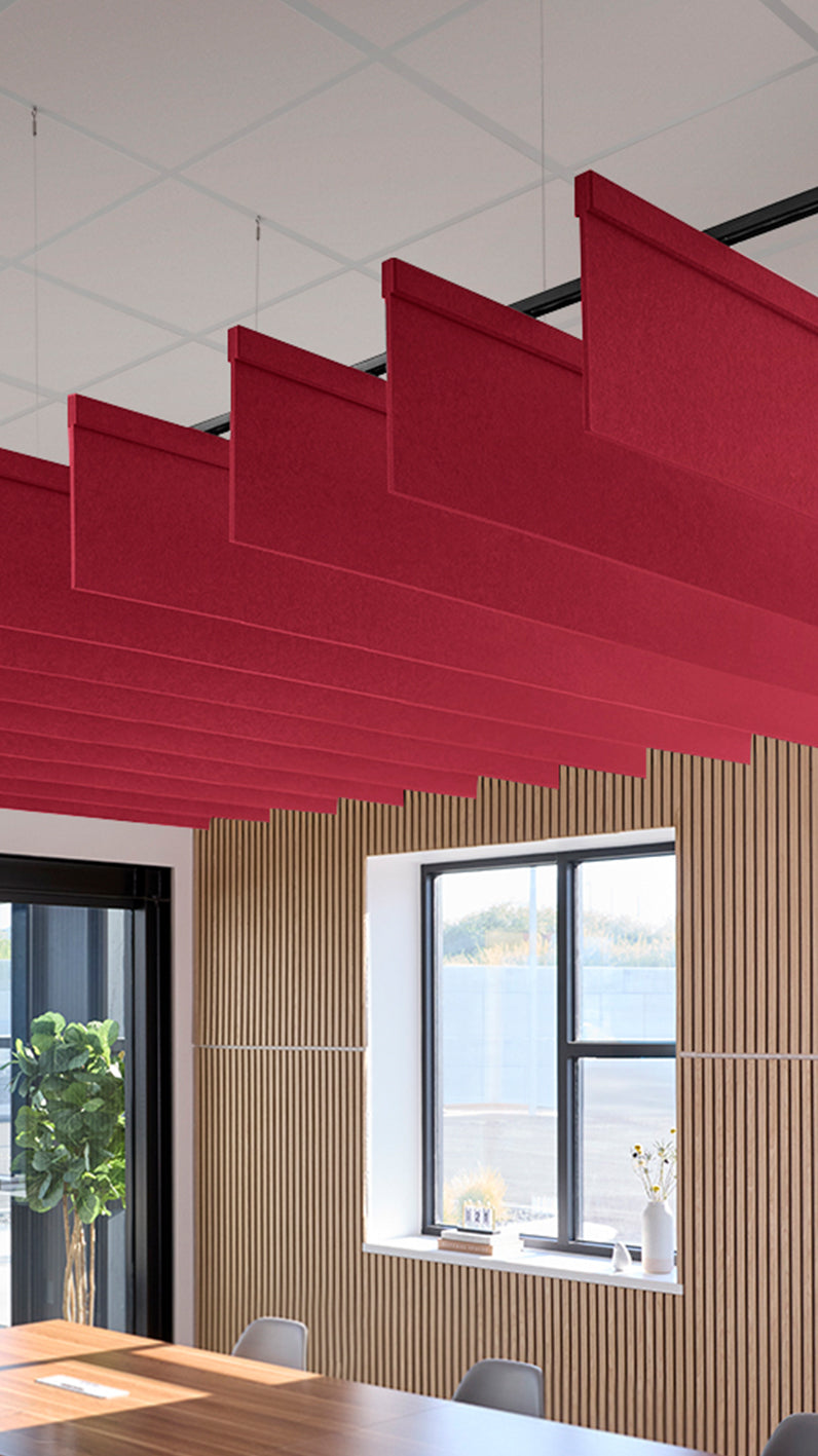 Red acoustic ceiling blade baffles suspended from the ceiling, installed in a conference room. Felt Right's acoustic blade baffles absorb 65% of sound waves, making office spaces quieter and feel more calm.