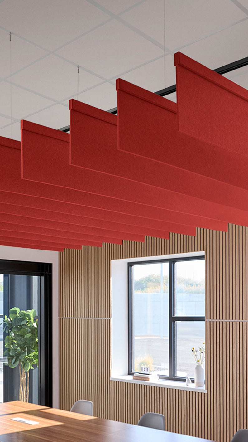 Bright red acoustic ceiling blade baffles suspended from the ceiling, installed in a conference room. Felt Right's acoustic blade baffles absorb 65% of sound waves, making office spaces quieter and feel more calm.