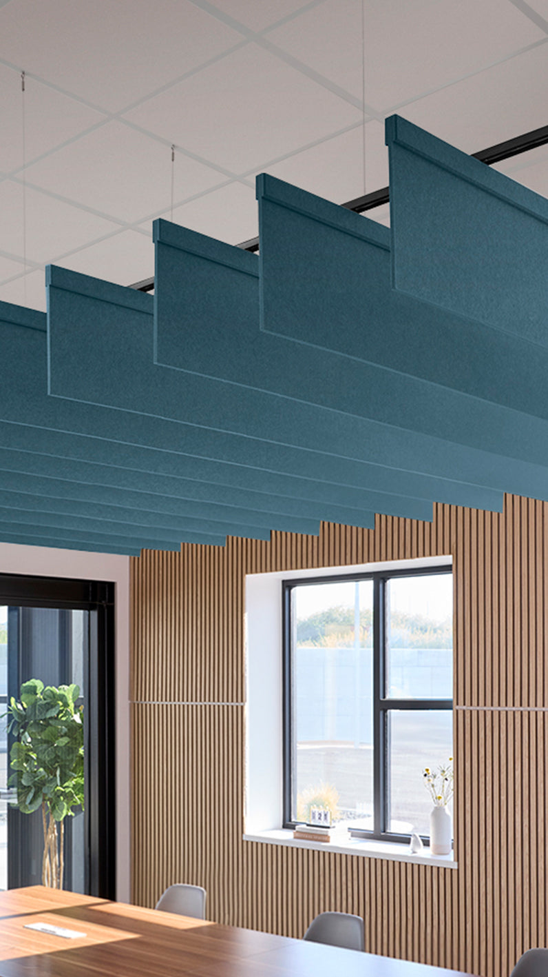 Teal acoustic ceiling blade baffles suspended from the ceiling, installed in a conference room. Felt Right's acoustic blade baffles absorb 65% of sound waves, making office spaces quieter and feel more calm.