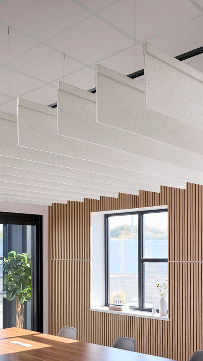 White acoustic ceiling blade baffles suspended from the ceiling, installed in a conference room. Felt Right's acoustic blade baffles absorb 65% of sound waves, making office spaces quieter and feel more calm.