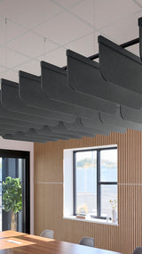Dark gray acoustic blade baffles suspended from ceiling above wooden wall paneling and windows.