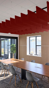 Red fin-shaped acoustic baffles suspended from ceiling above conference table in office space.