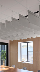 Gray fabric acoustic baffles with curved fins suspended from ceiling in office space with wood wall paneling.