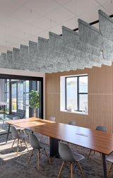 A modern conference room with a long wooden table, gray chairs, a slatted wood wall, and a large sculptural gray ceiling light fixture.