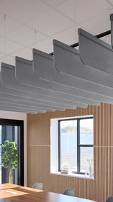 Gray fabric acoustic baffles with curved edges suspended from ceiling in modern office space.