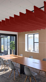Red fin-shaped acoustic baffles suspended from ceiling in modern office conference room with wood table and chairs.