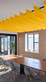 Yellow acoustic fin baffles suspended from ceiling above conference table in modern office space.