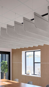Gray fabric acoustic baffles with curved edges suspended from ceiling grid in modern office space.