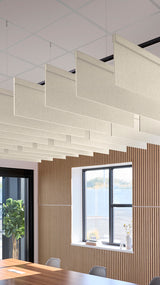 Cream-colored rectangular acoustic baffles suspended from ceiling in staggered rows above wooden wall paneling.