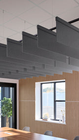 Dark gray acoustic baffles suspended from ceiling in modern office space with wood wall paneling and windows.