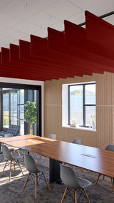 Red fabric acoustic baffles suspended from ceiling in office meeting room with conference table.