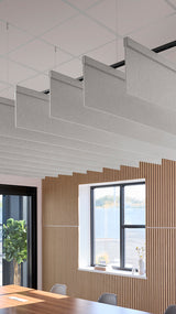 Gray acoustic blade baffles suspended from ceiling in modern office space with wooden wall paneling.