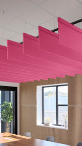 Pink fabric acoustic baffles suspended from ceiling in straight horizontal alignment above interior office space.
