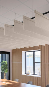 Beige acoustic baffles suspended from ceiling in modern office space with wooden wall paneling and windows.