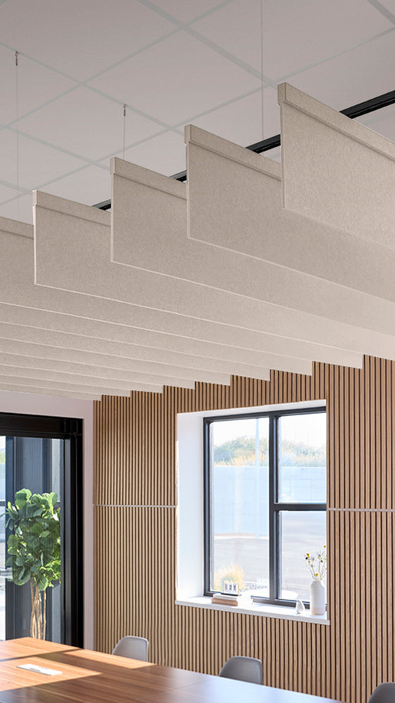 Beige acoustic baffles suspended from ceiling in modern office space with wooden wall paneling and windows.