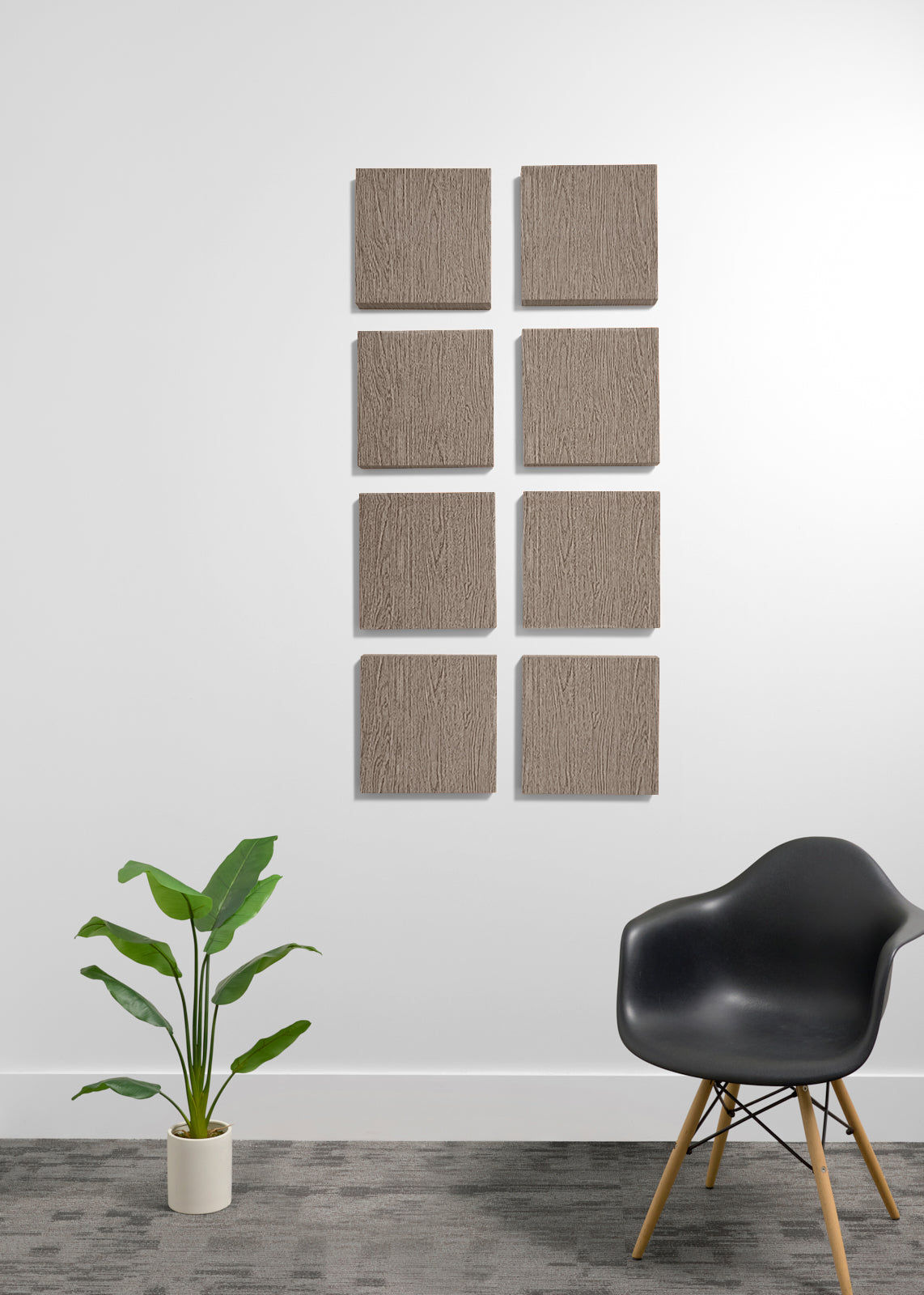 Eight square textured wall panels in a warm taupe-brown color arranged in two columns of four on a white wall, styled in a modern room with a black chair and a potted green plant.
