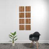 Eight wood-grain acoustic panels arranged in a 2x4 grid on a white wall above a black chair and potted plant.