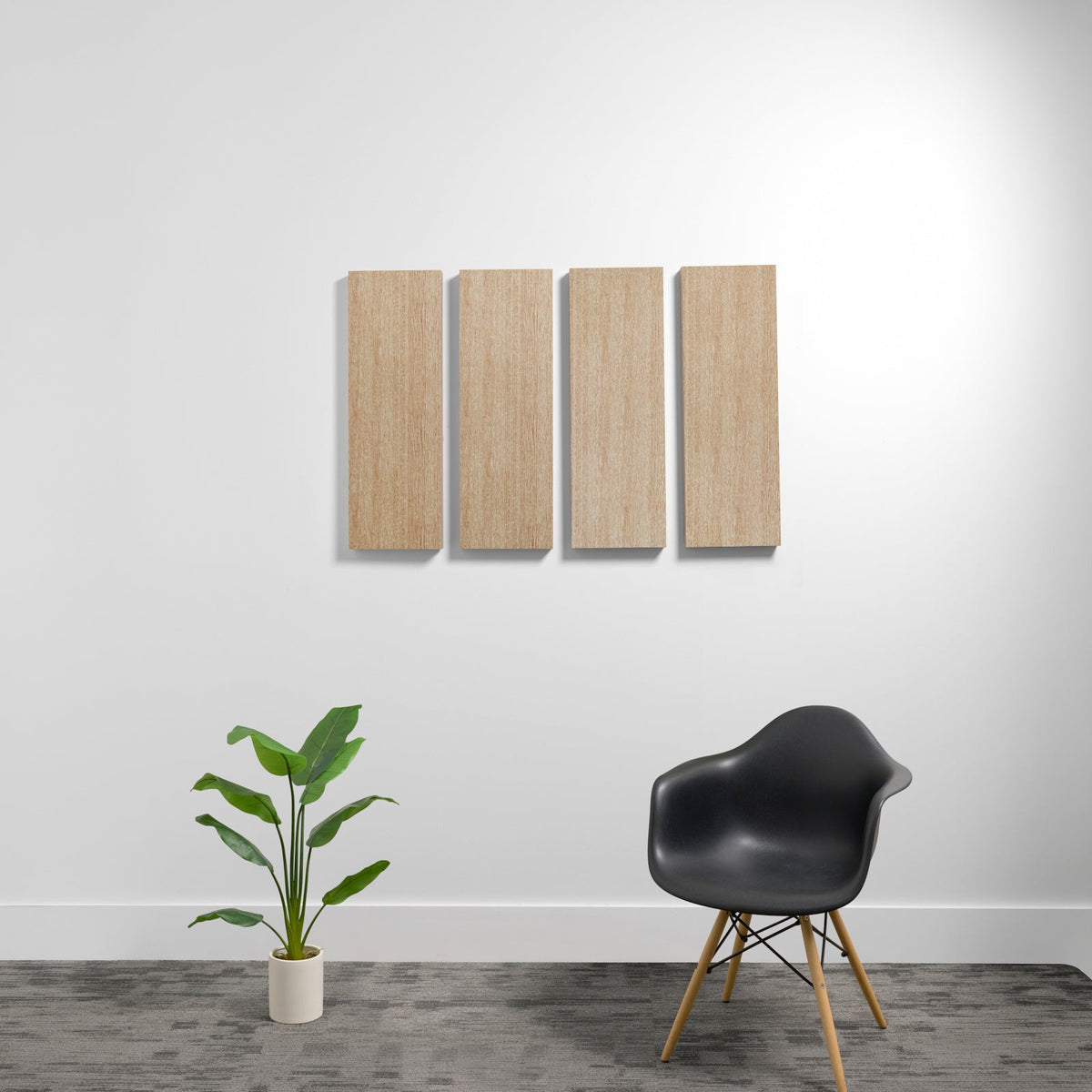 Four rectangular wooden acoustic panels mounted on white wall above chair and plant.