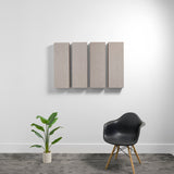 Four rectangular beige acoustic panels mounted on white wall above black chair and potted plant.