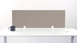Beige desk divider with wavy cutout pattern, mounted on white desk with metal brackets.