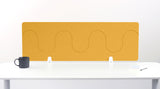 Mustard yellow desk divider with wave-shaped cutouts mounted on white desk with coffee mug and notepad.