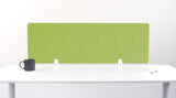 Green wave-patterned desk divider with white mounting brackets on white desk surface.
