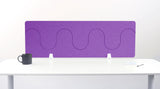 Purple desk divider with wavy cutout pattern mounted on white desk with supports.