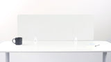 Wave-shaped translucent desk divider with white supports mounted on white desk surface.