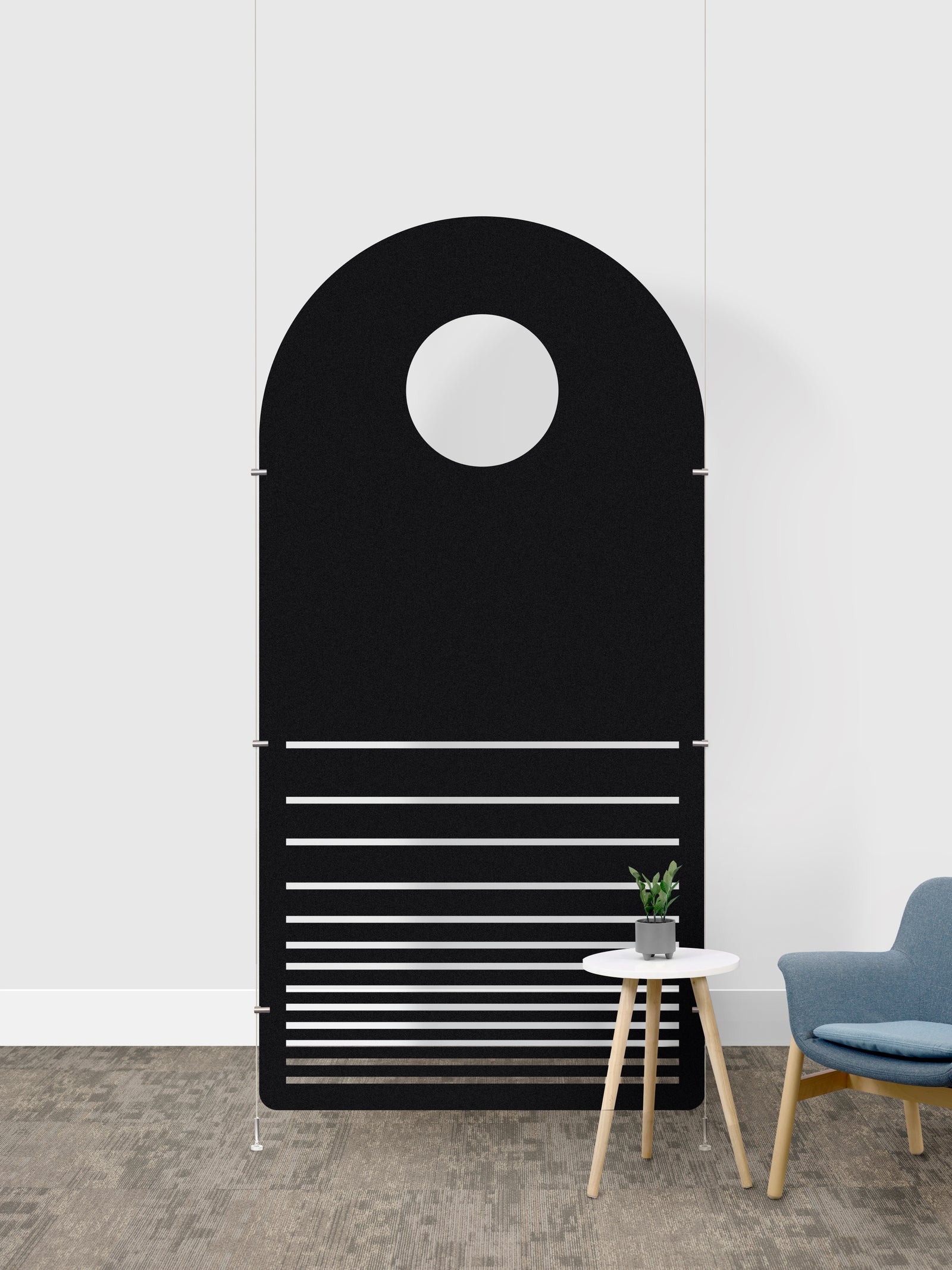 A modern black arched wall panel with a circular cutout near the top and horizontal slats across the lower half, shown in a minimalist room setting next to a small side table and blue chair.