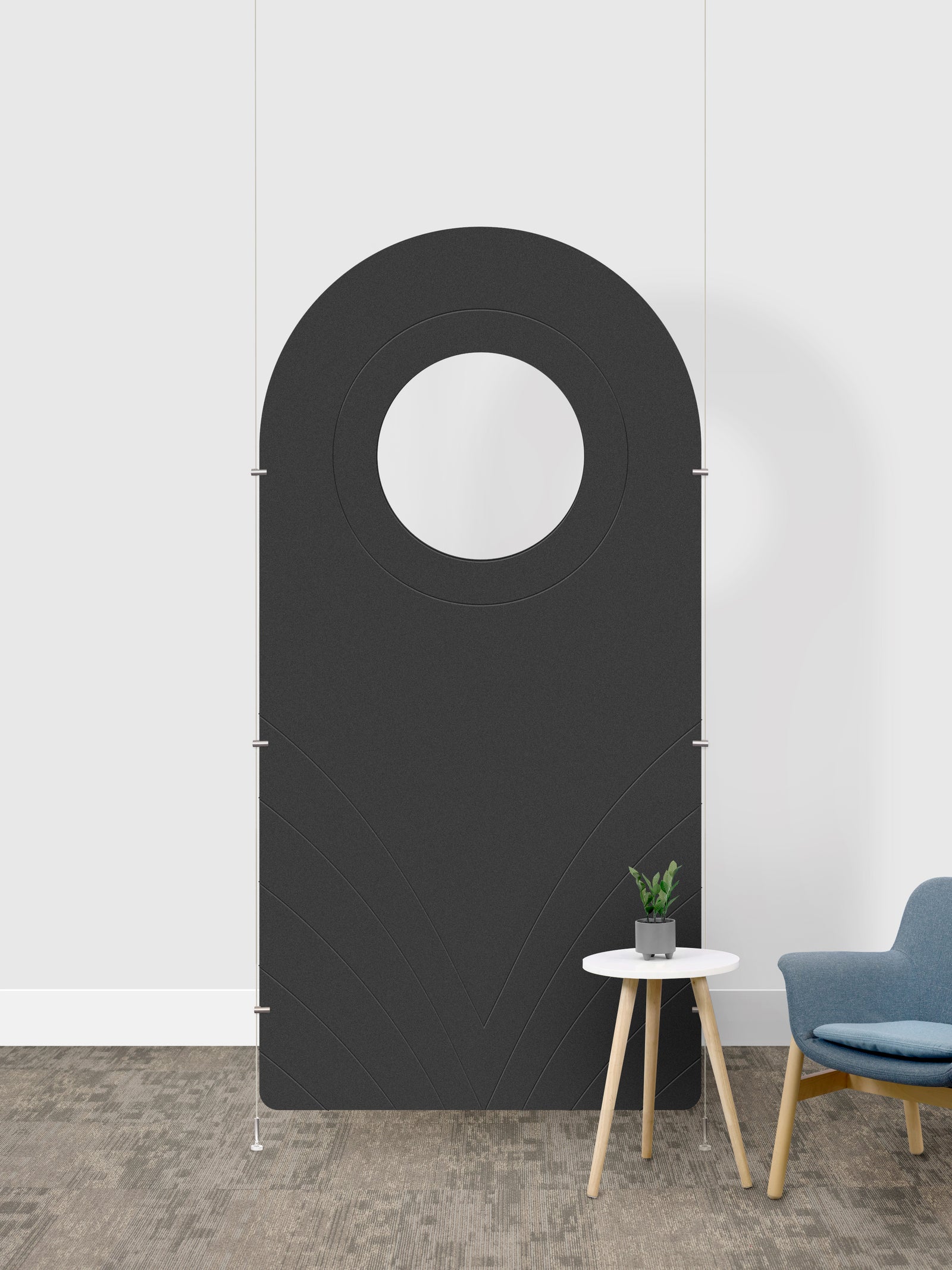 A dark gray arched room divider panel with a circular cutout in the center, shown in a room setting next to a small side table and a blue chair.