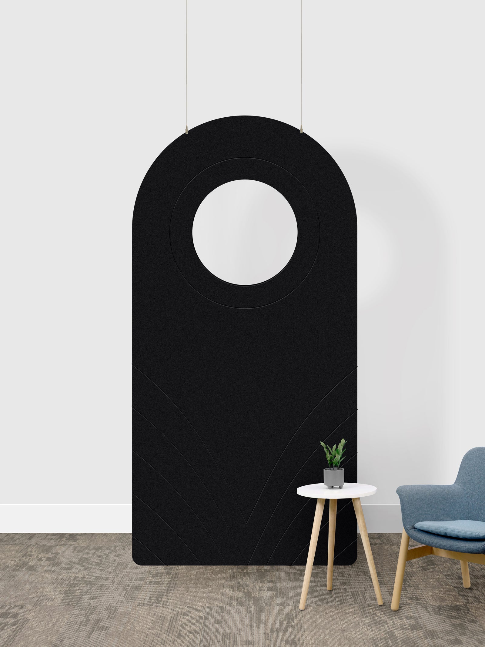 A black arched room divider panel with a circular cutout in the center, shown in a room setting next to a small side table and a blue chair.