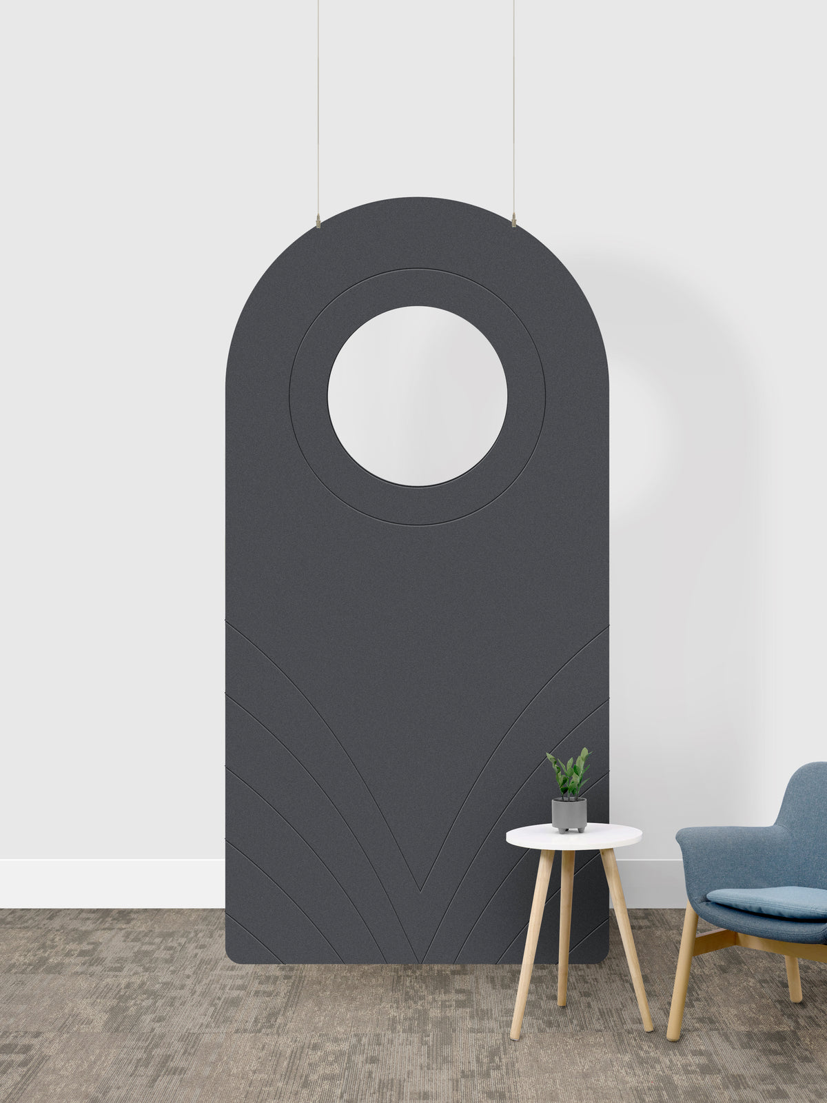 A dark gray arched room divider panel with a circular cutout in the center, shown in a room setting next to a small side table and a blue chair. 