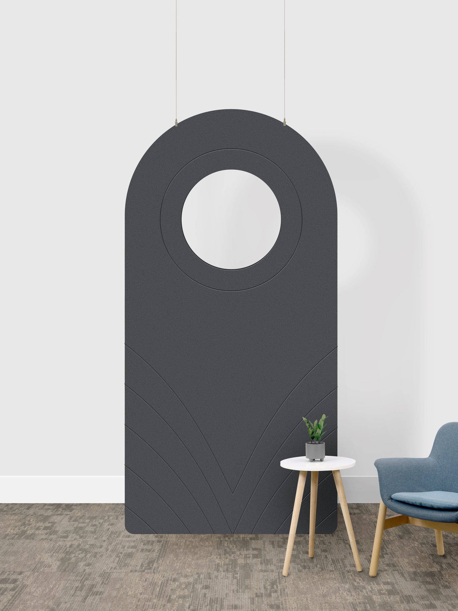 A dark gray arched room divider panel with a circular cutout in the center, shown in a room setting next to a small side table and a blue chair. 